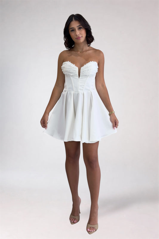 Woman wearing a white strapless dress on a plain background
