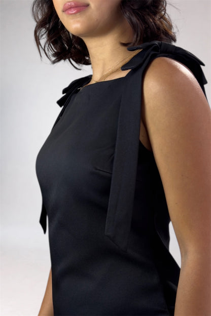 Black sleeveless top with bow details on a plain background