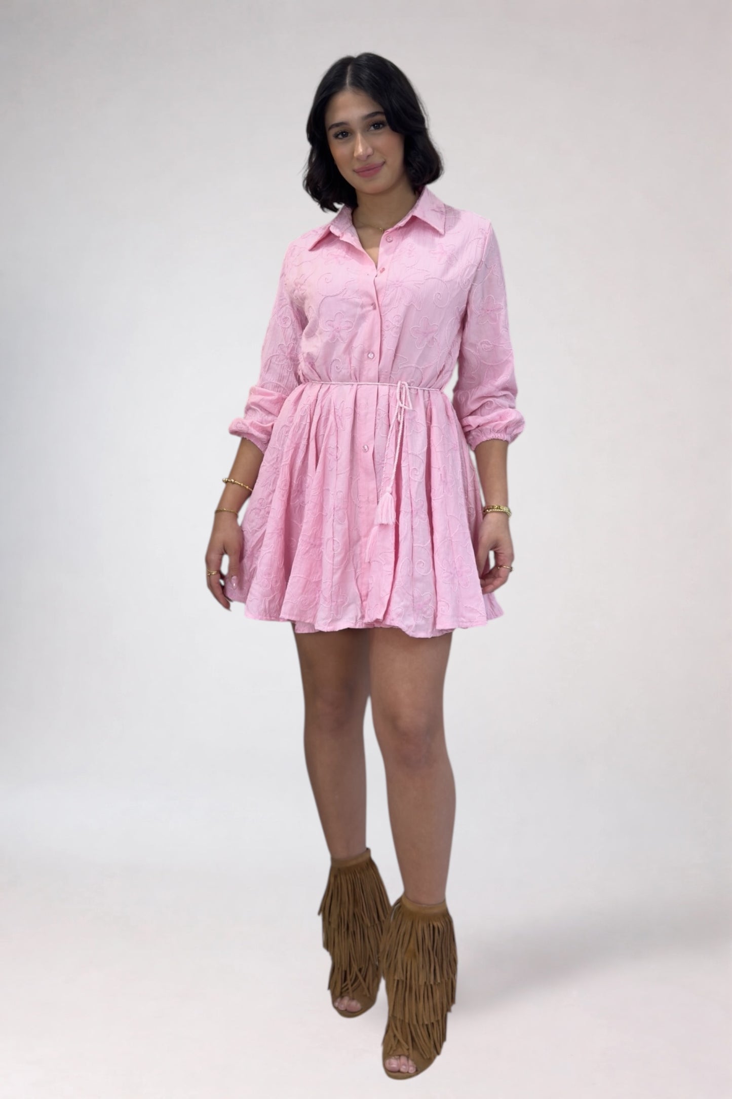 Woman wearing a pink dress with long sleeves on a white background