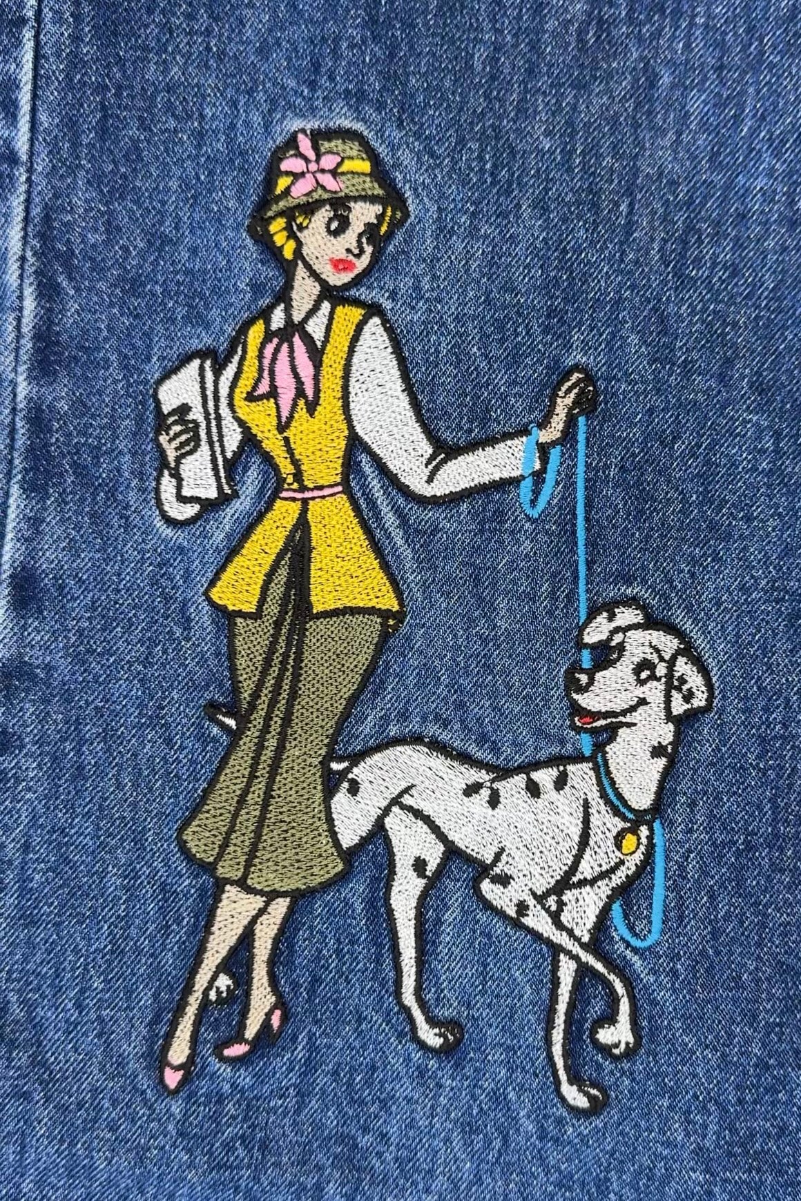 Embroidered design on denim fabric of a woman walking a Dalmatian dog.