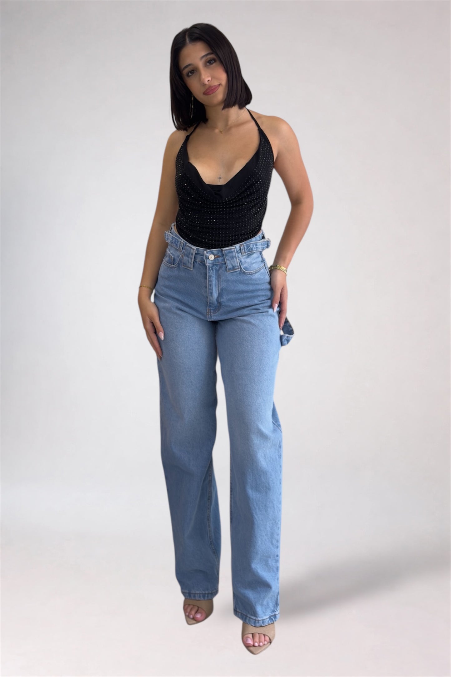 Woman wearing a black tank top and light blue jeans on a white background