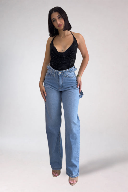 Woman wearing a black tank top and light blue jeans on a white background