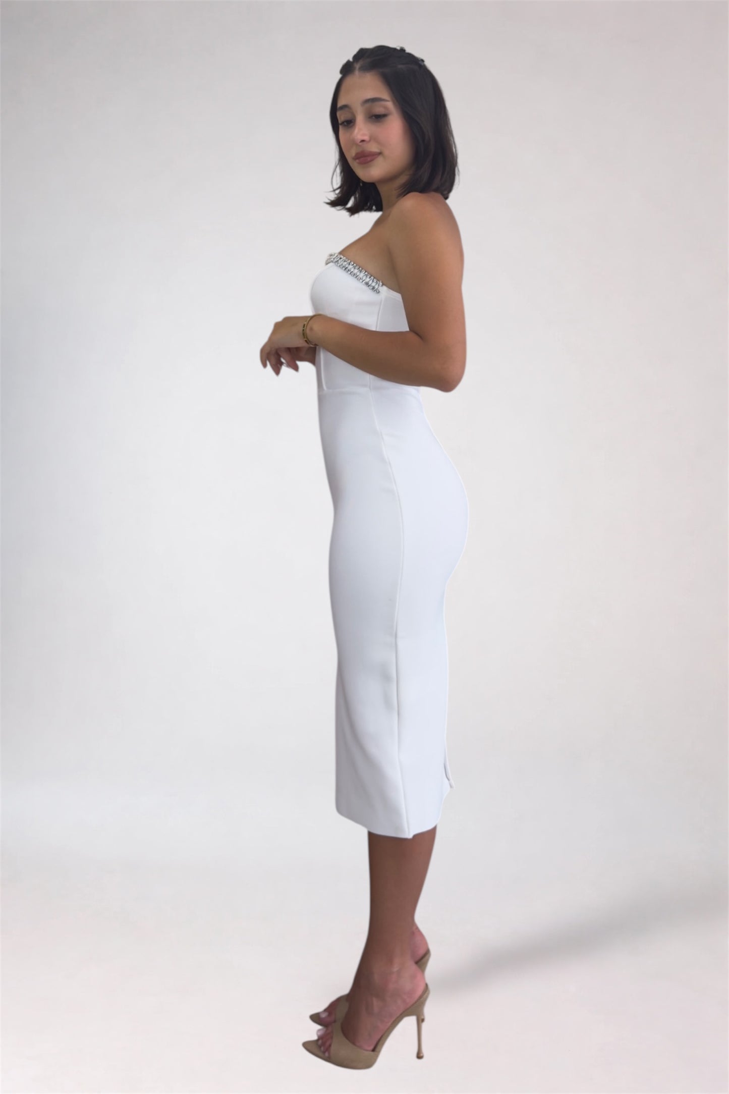 Woman wearing a strapless white dress with a plain background