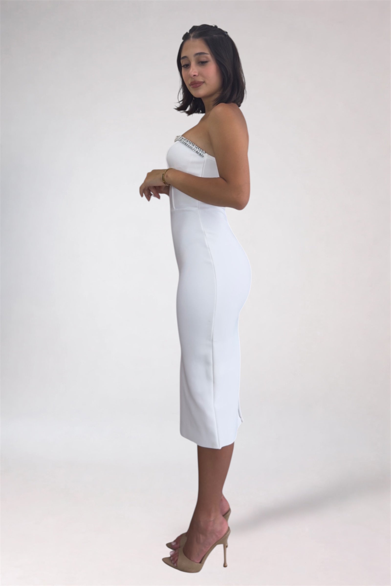 Woman wearing a strapless white dress with a plain background