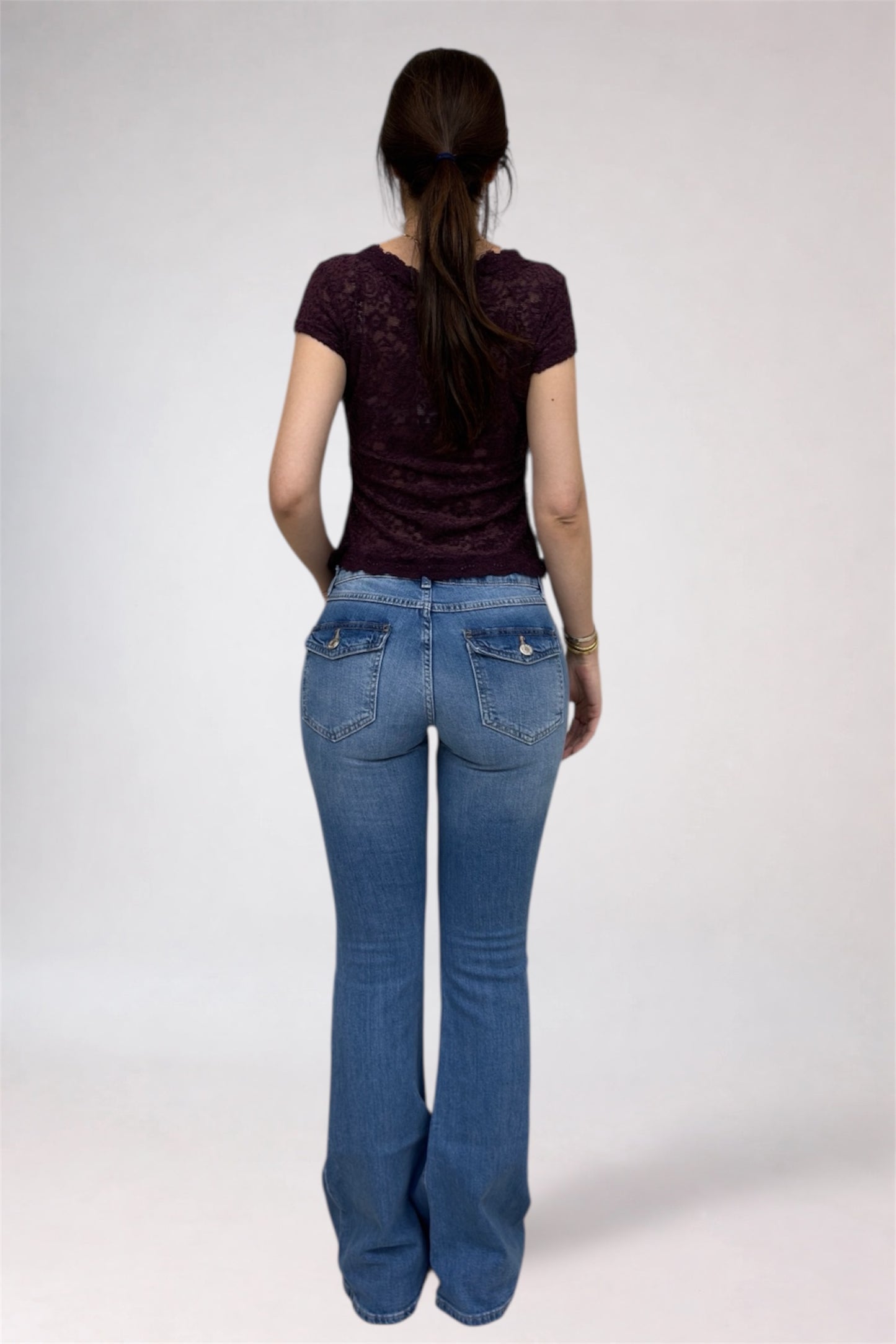 Person wearing a dark top and blue jeans on a white background
