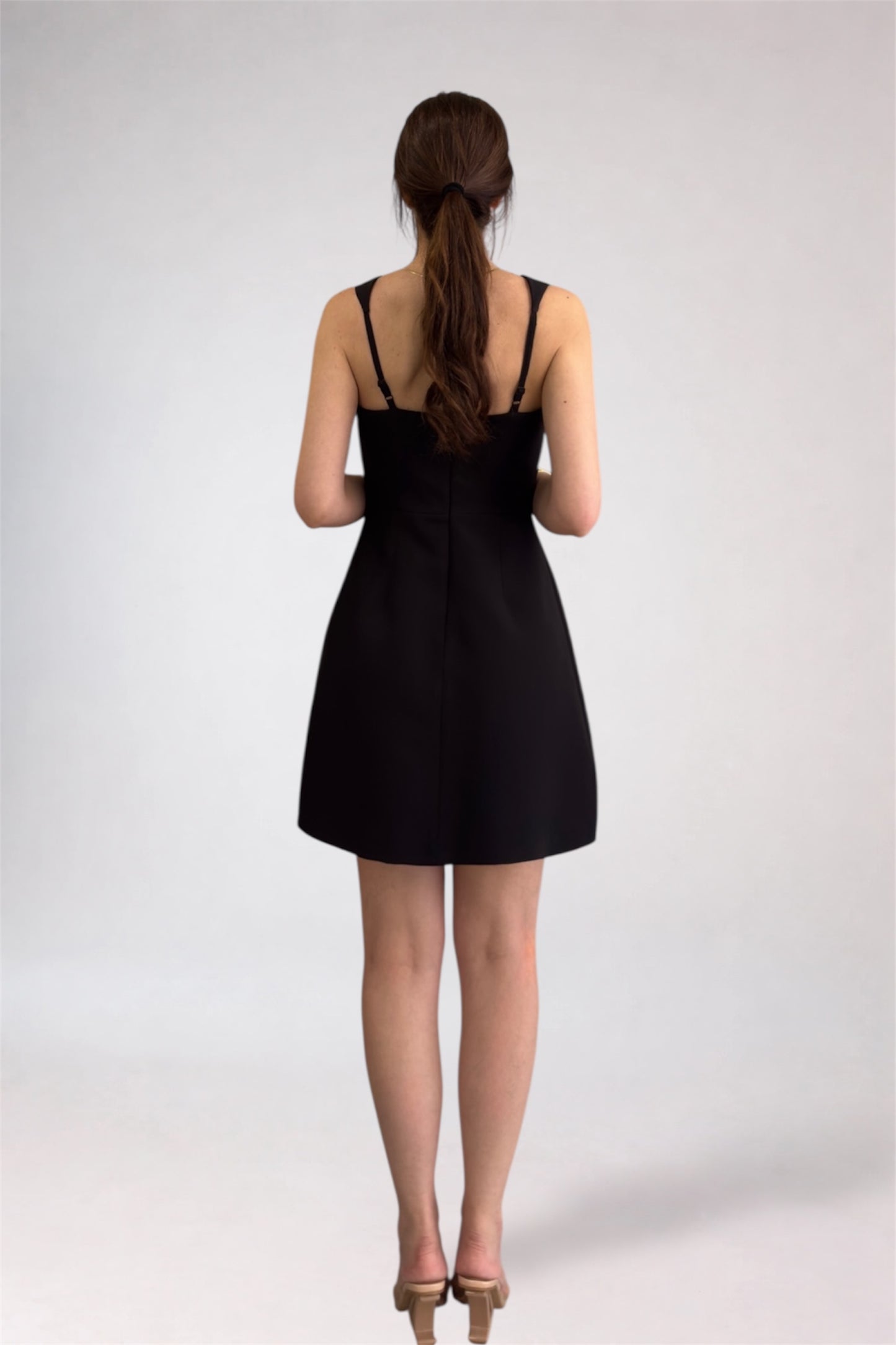 Woman wearing a black dress from behind on a white background