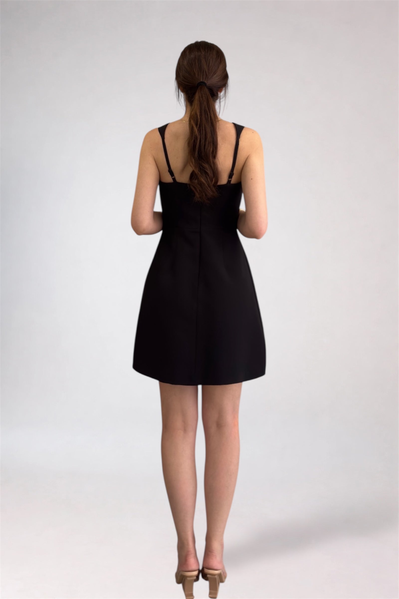 Woman wearing a black dress from behind on a white background