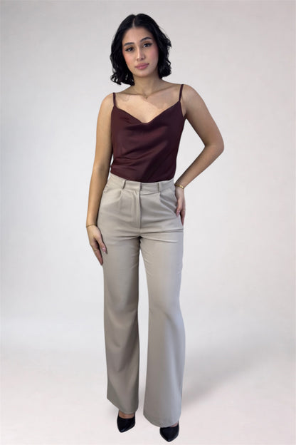 Woman wearing a brown top and beige pants against a white background