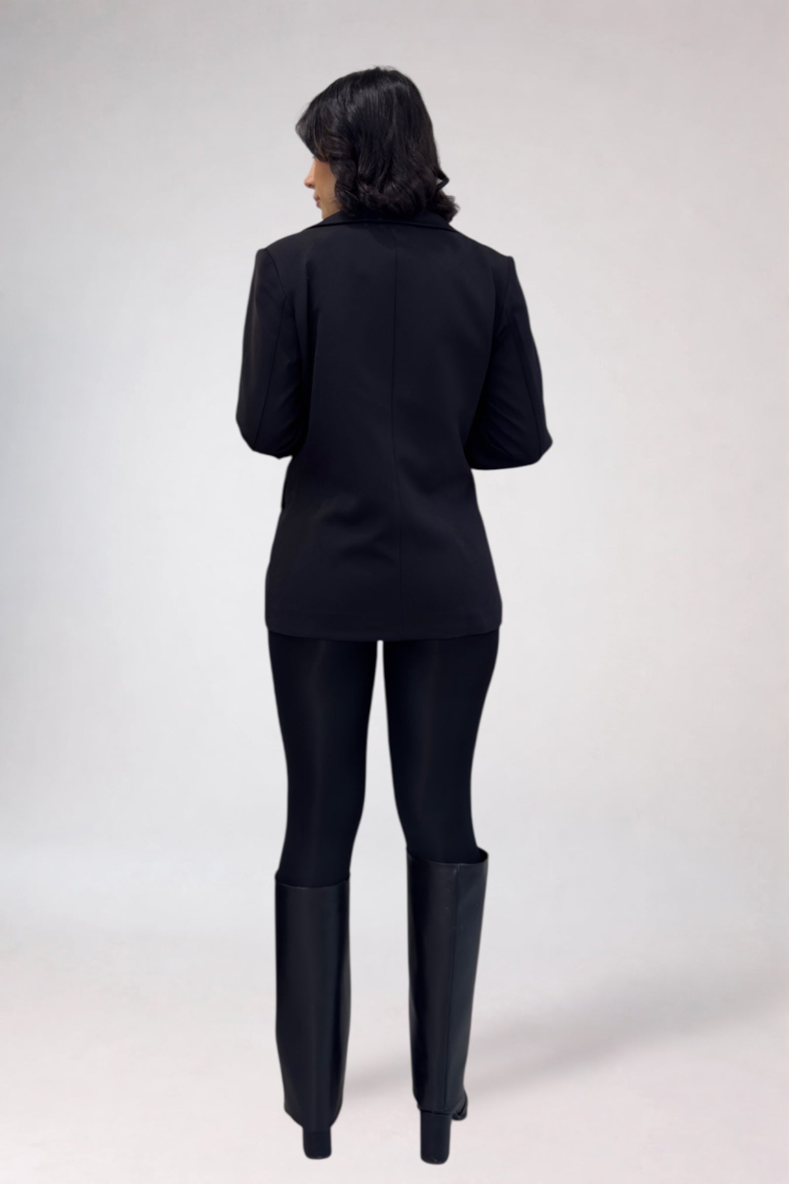 Person wearing a black suit with long boots on a white background