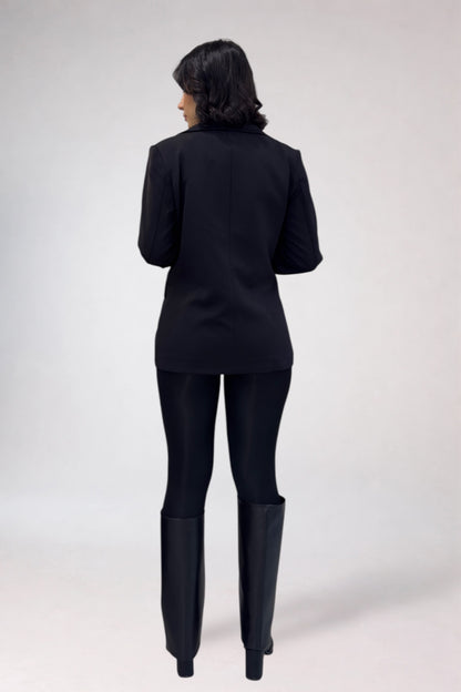 Person wearing a black suit with long boots on a white background