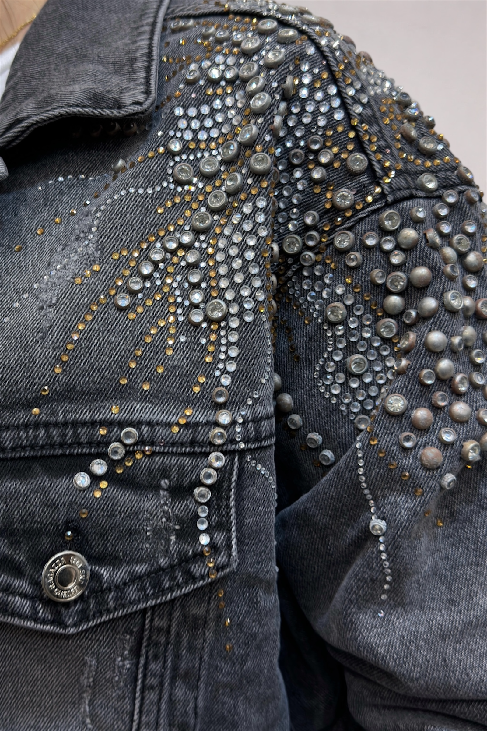 Close-up of a denim jacket with silver studs and decorative elements.