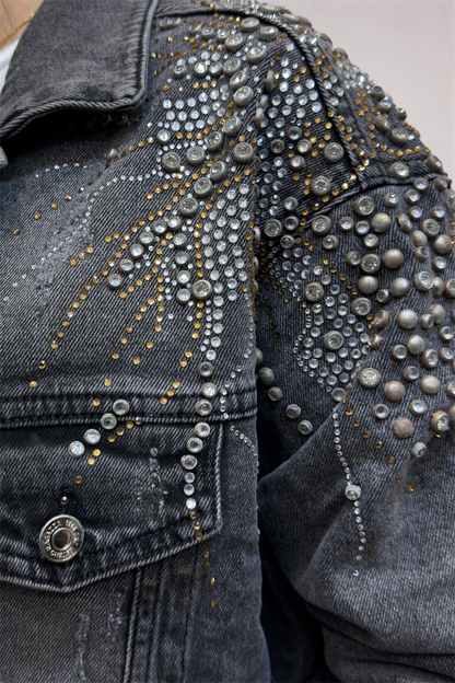 Close-up of a denim jacket with silver studs and decorative elements.