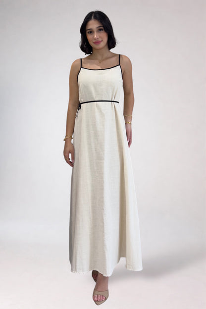 Woman wearing a white dress with black straps on a plain background