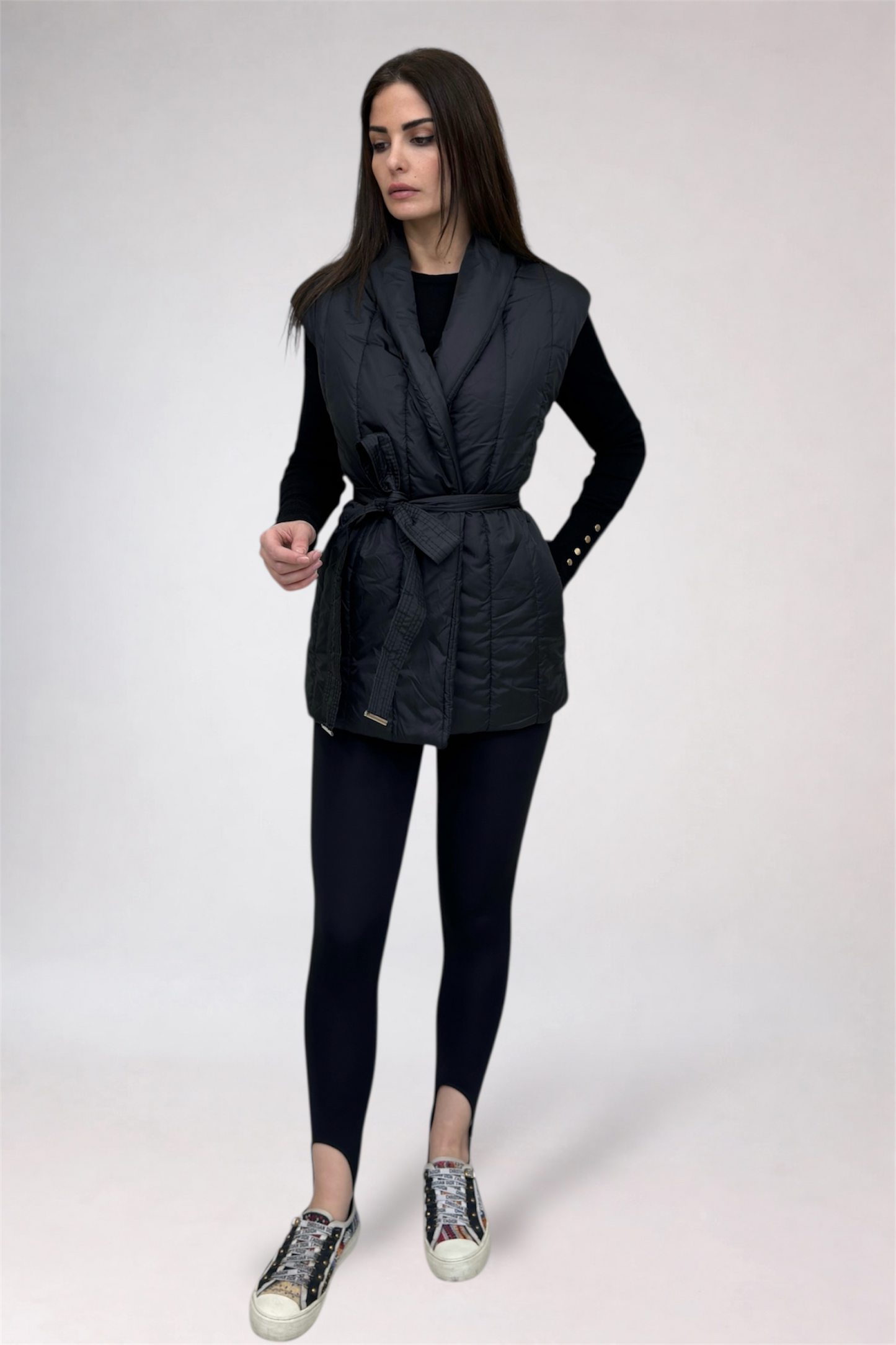 Woman wearing a black puffer vest and leggings on a white background