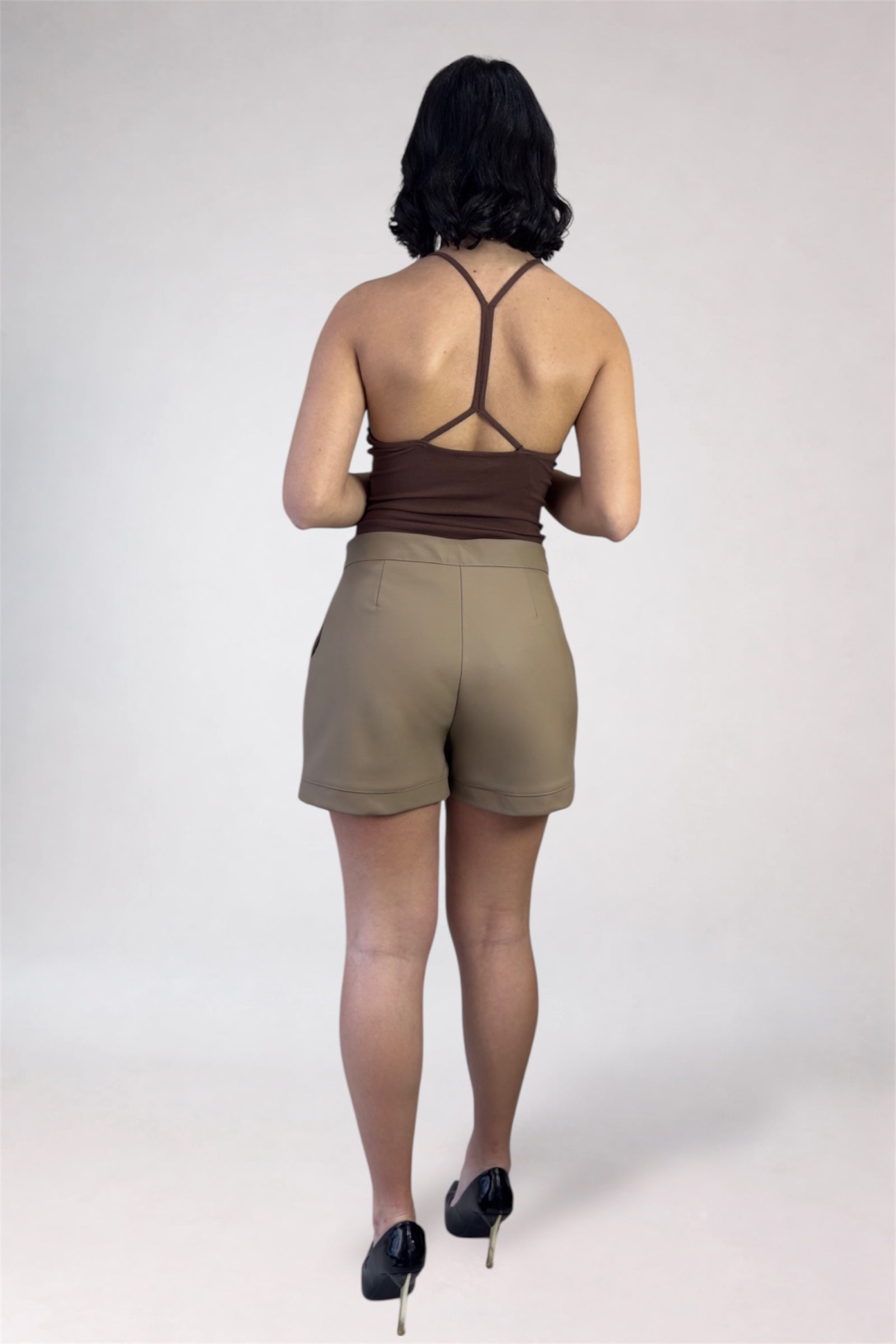 Person wearing a brown top and beige shorts on a white background