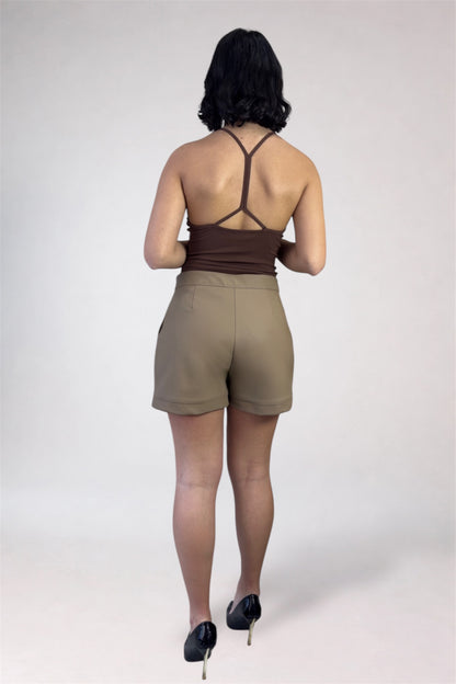 Person wearing a brown top and beige shorts on a white background