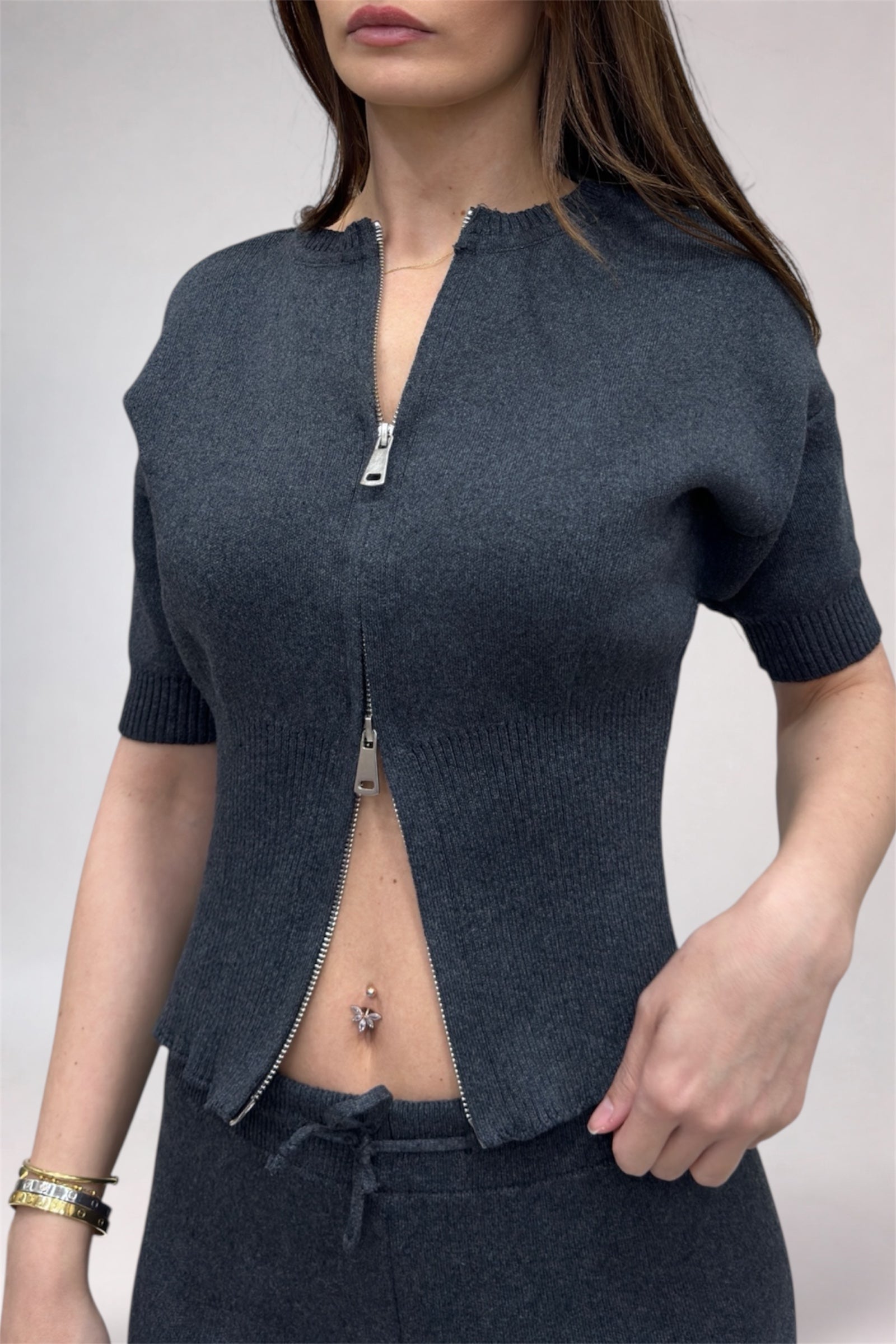 Woman wearing a dark blue knitted cardigan with a zipper on a plain background