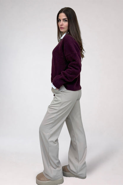 Woman wearing a purple sweater and light gray pants on a white background
