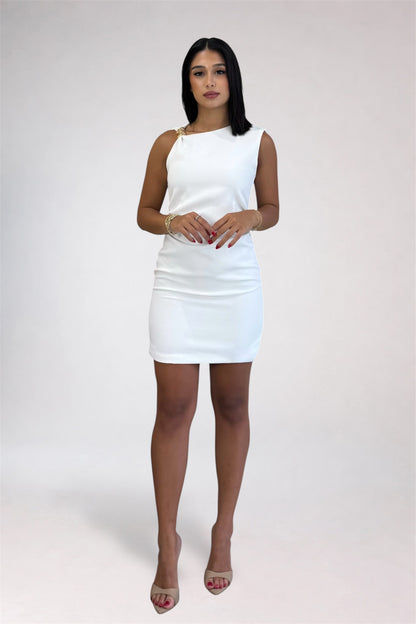 A woman modeling a white sleeveless bodycon mini dress with a single gold-tone ring detail at the shoulder, paired with nude high-heeled sandals, against a light gray studio background.