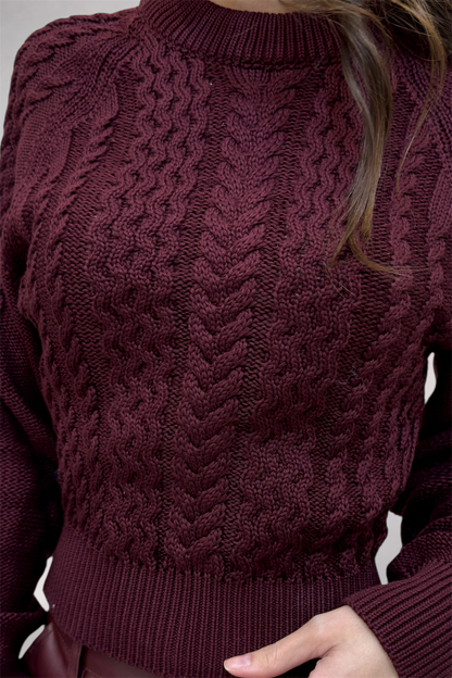 Close-up of a person wearing a cable knit burgundy sweater.