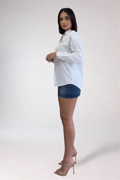 Woman wearing a white blouse and denim shorts on a plain background
