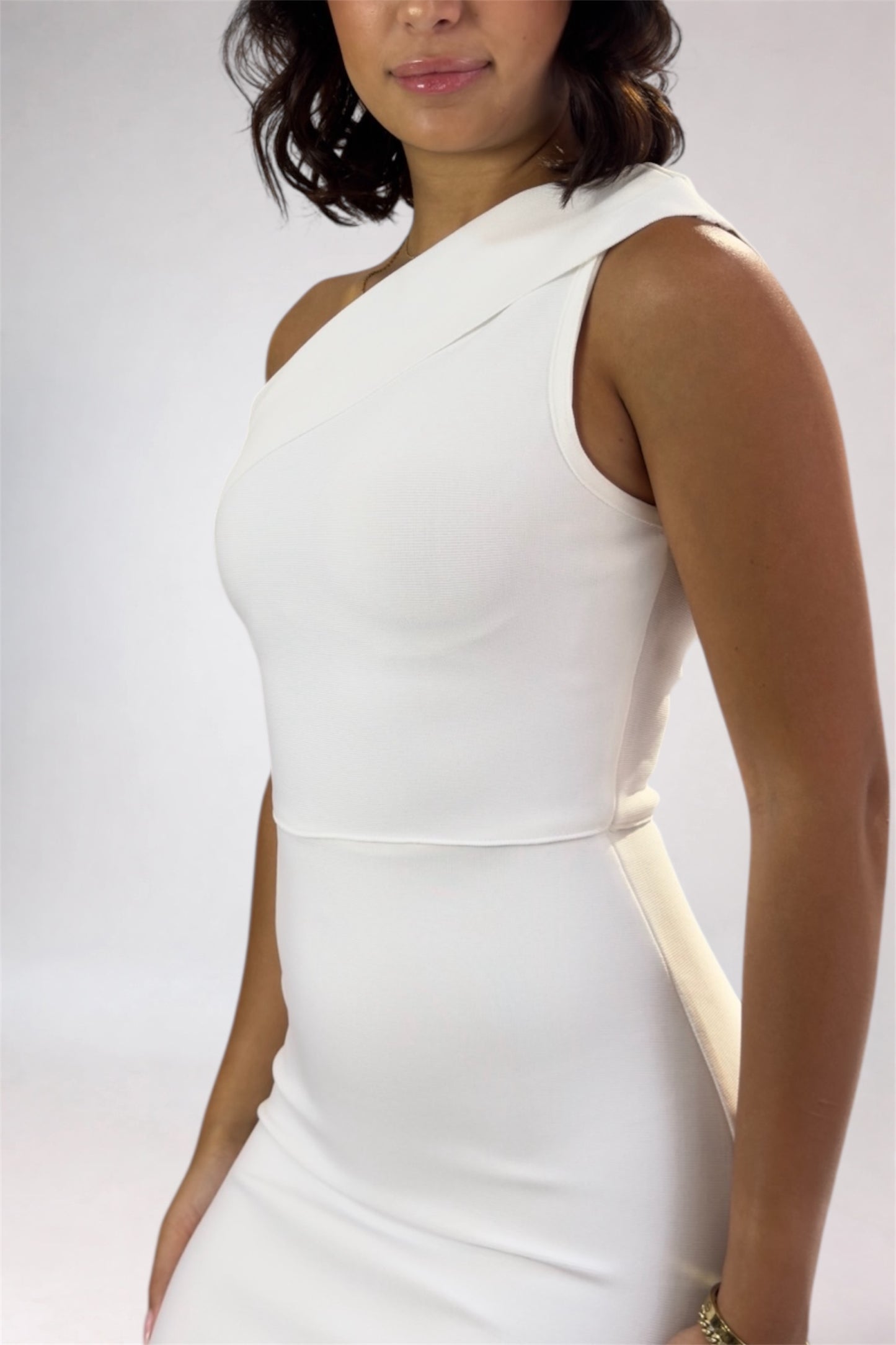 Woman wearing a white sleeveless dress against a plain background
