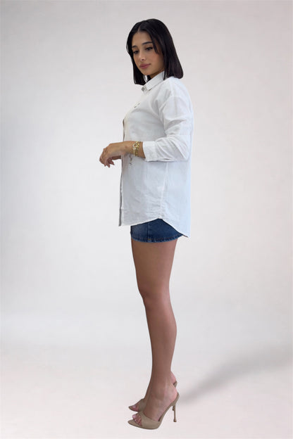 Woman wearing a white blouse and denim shorts on a plain background