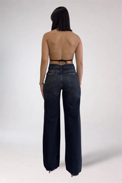 Person wearing dark blue jeans on a plain background