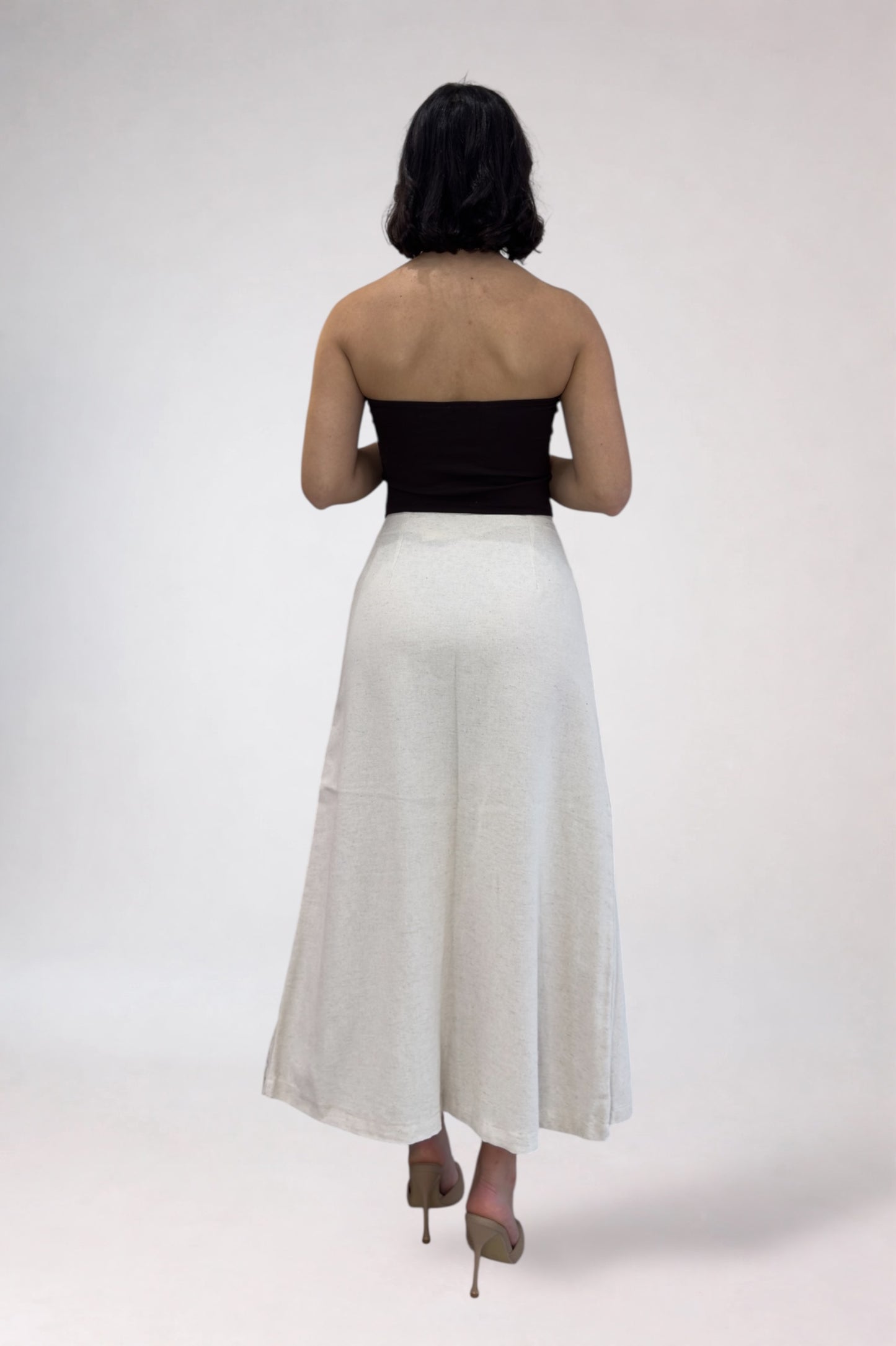 Woman wearing a black top and white skirt on a white background