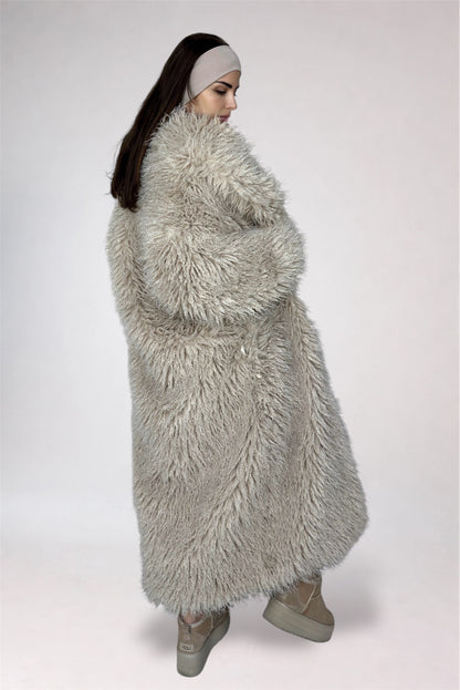 Person wearing a long, fluffy gray coat on a plain background