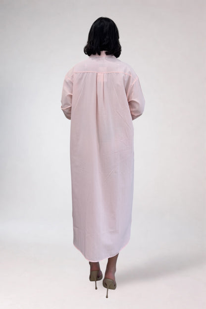 Person wearing a light pink dress with sheer sleeves on a white background