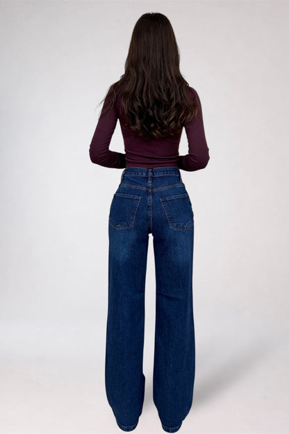 Person wearing blue jeans and a maroon top on a white background
