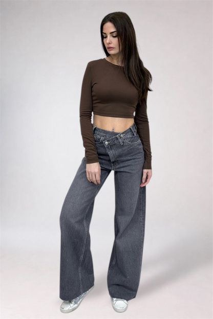 Woman wearing a brown long-sleeve top and gray jeans on a white background