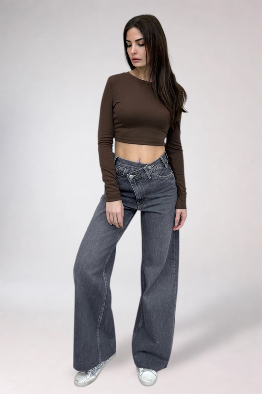 Woman wearing a brown long-sleeve top and gray jeans on a white background