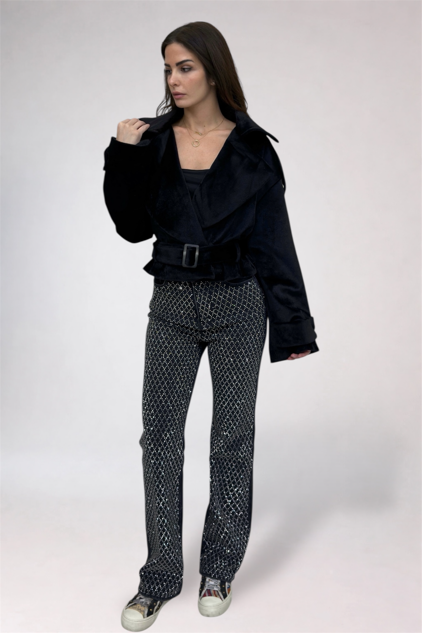 Woman wearing a black jacket and patterned pants on a white background