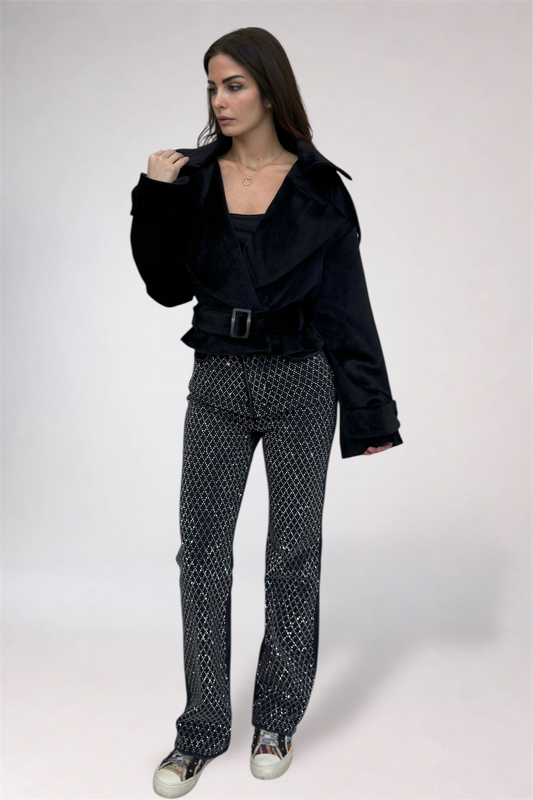 Woman wearing a black jacket and patterned pants on a white background