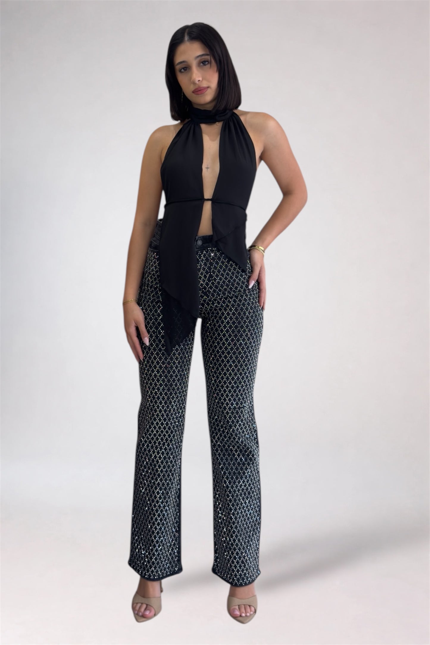 Woman wearing a black halter top and patterned pants on a white background