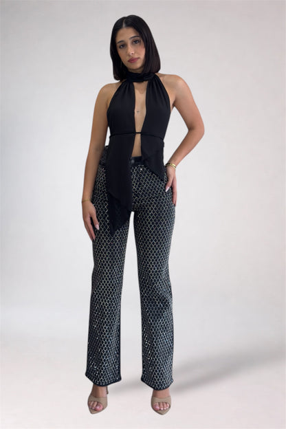 Woman wearing a black halter top and patterned pants on a white background