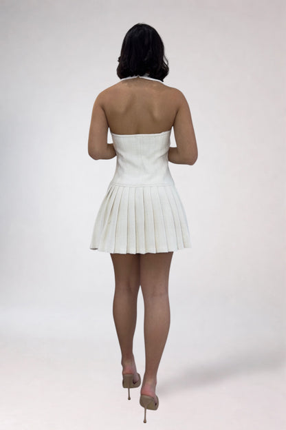 Person wearing a white pleated dress on a plain background