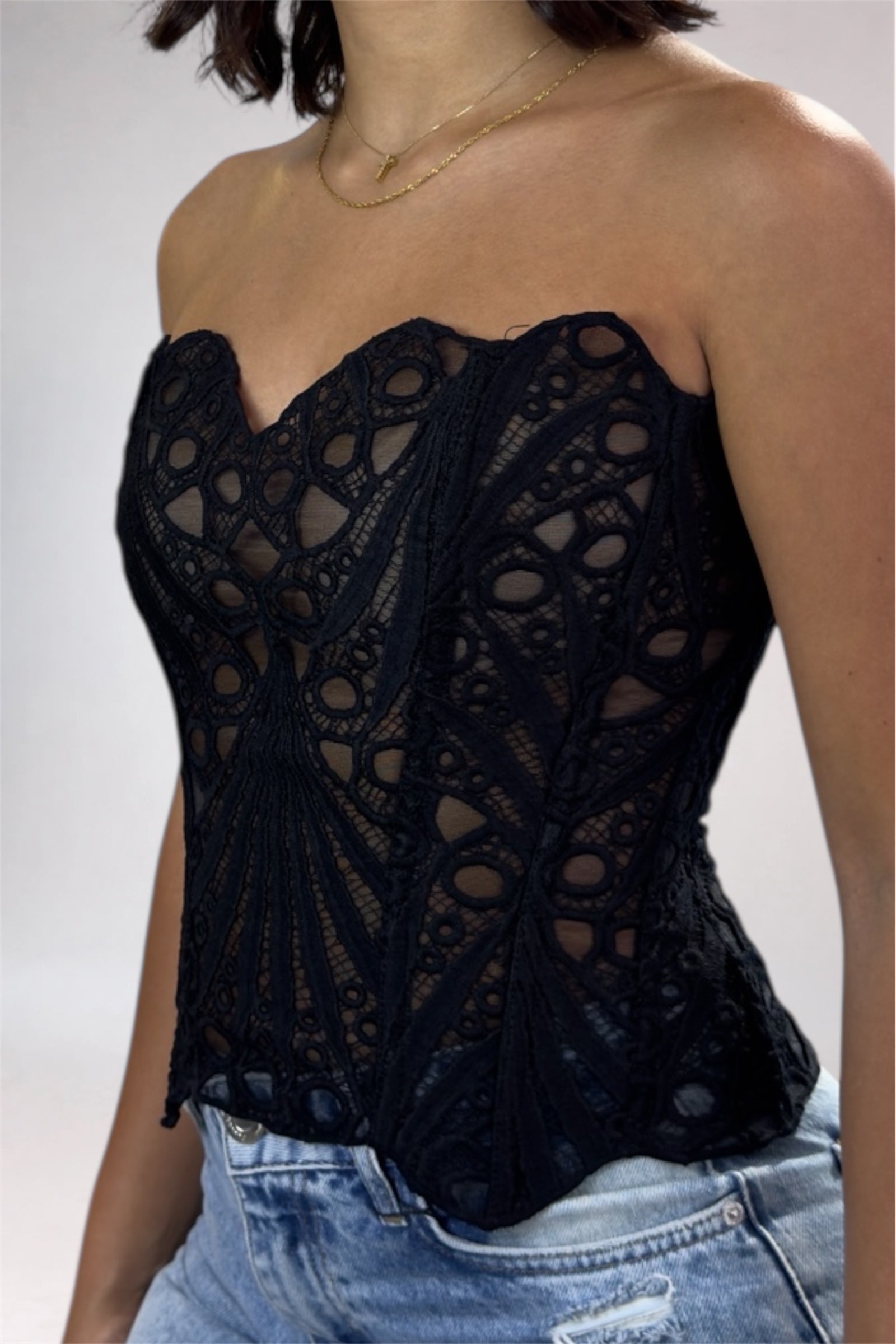 Black lace top worn by a person on a plain background