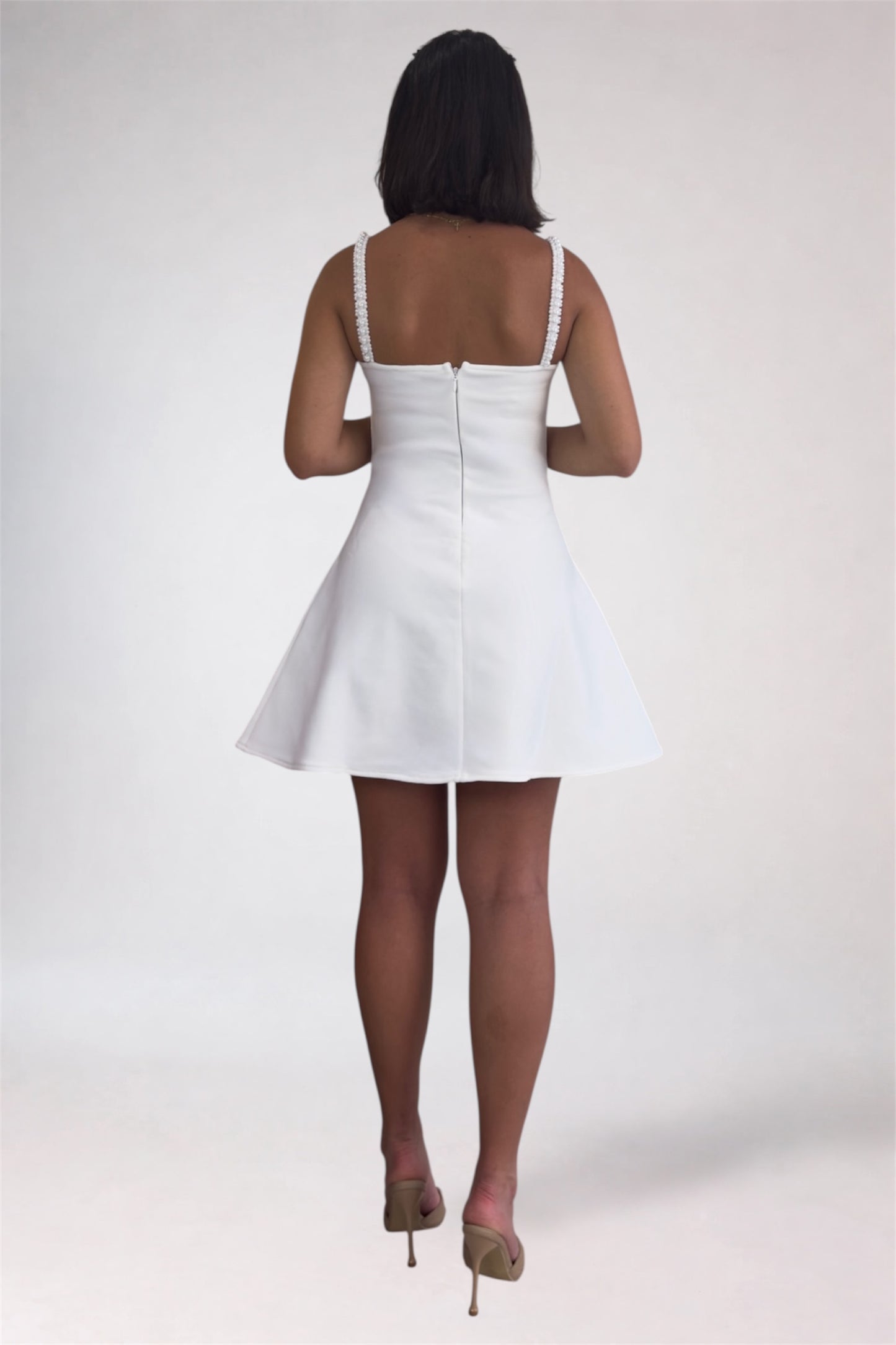 Person wearing a white dress on a plain background