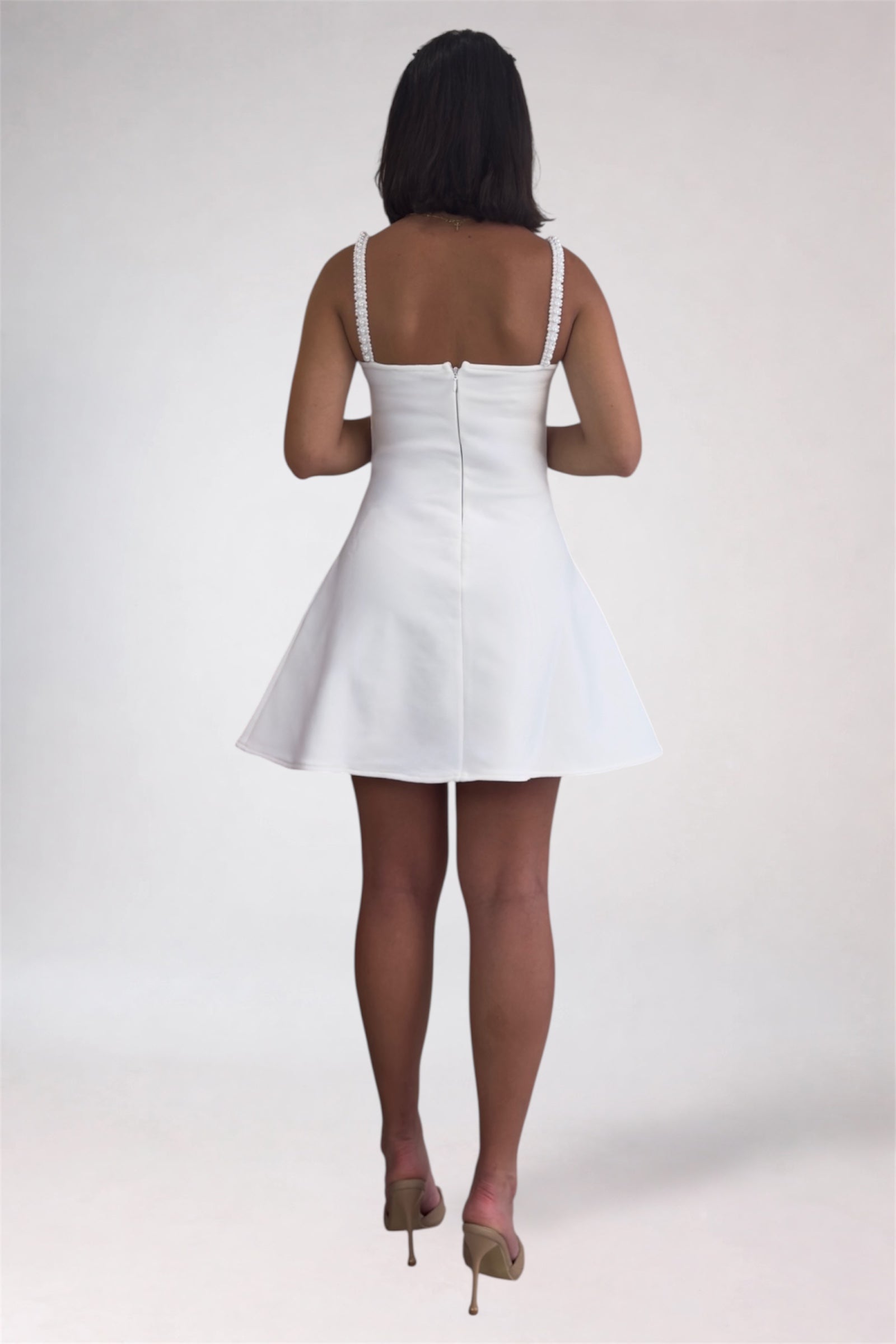 Person wearing a white dress on a plain background