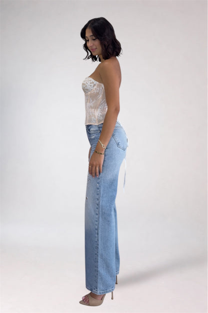Woman wearing a white lace top and light blue jeans on a white background