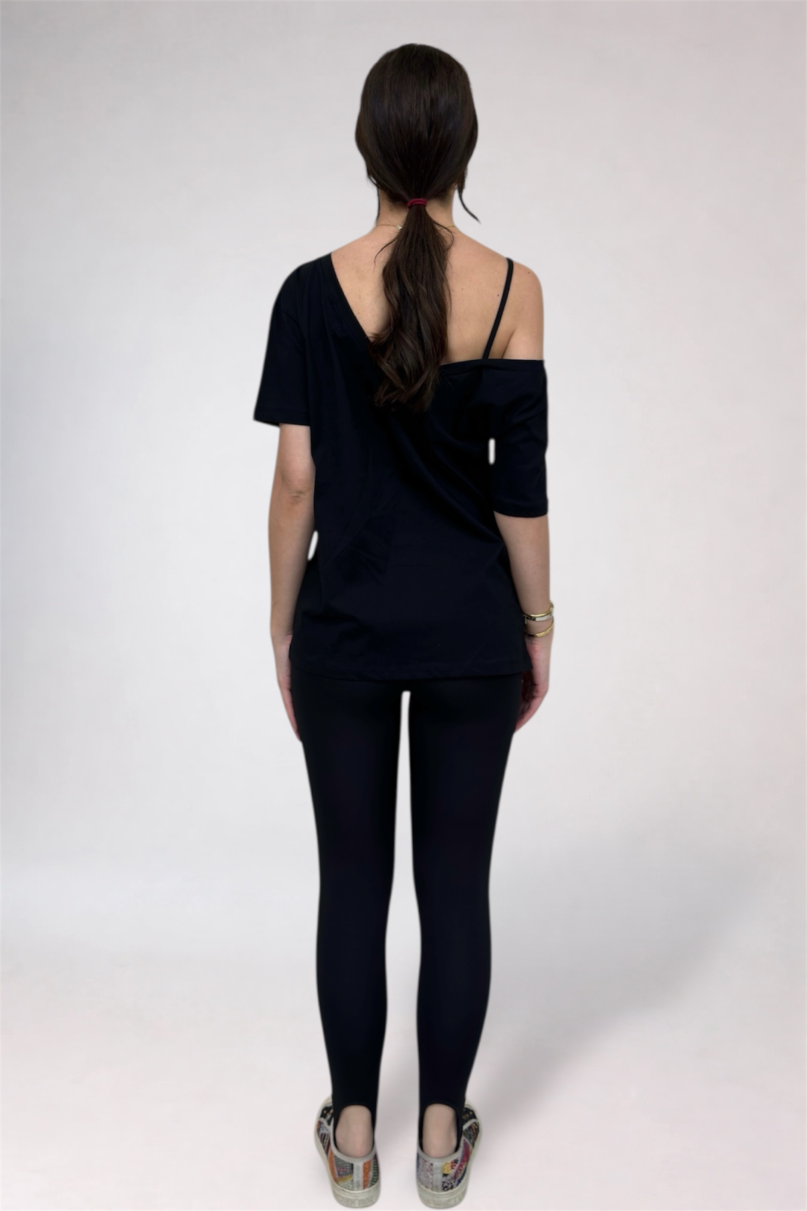 Person wearing a black off-shoulder top and leggings on a white background