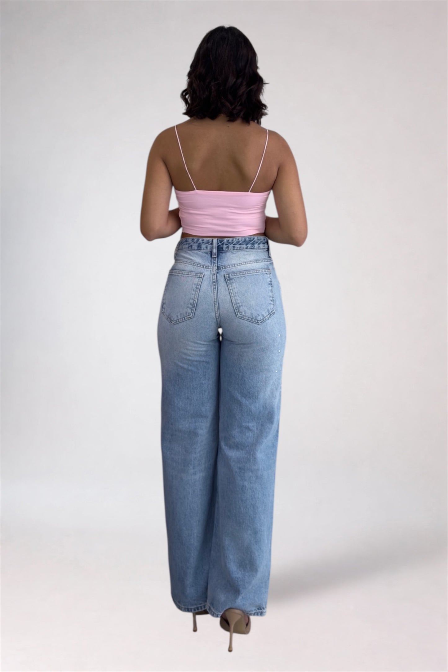 Person wearing a pink top and light blue jeans on a white background