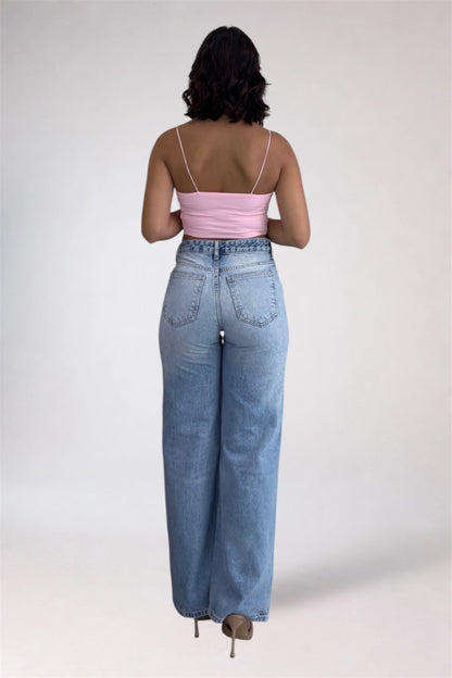 Person wearing a pink top and light blue jeans on a white background