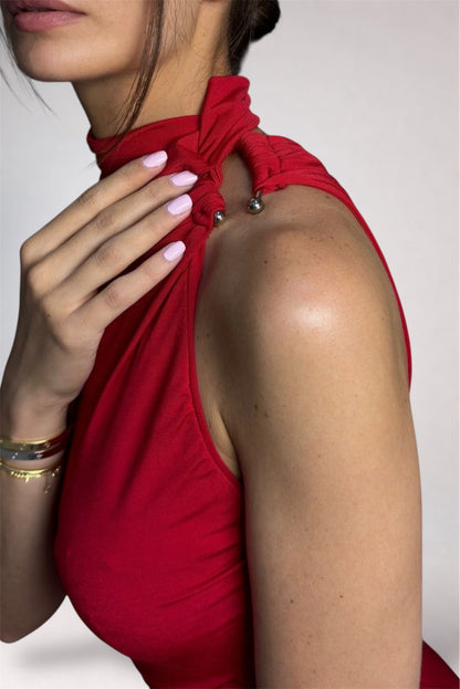 Close-up of a person wearing a red halter top with a plain background
