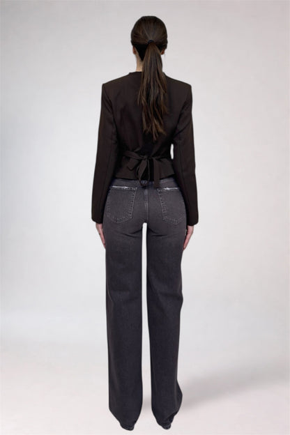 Person wearing a black blazer and dark jeans from behind on a white background