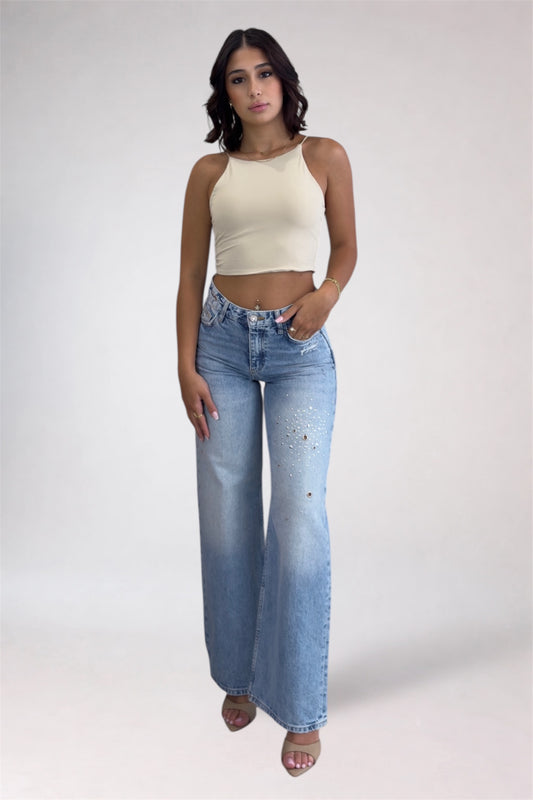 Woman wearing a beige top and blue jeans on a white background