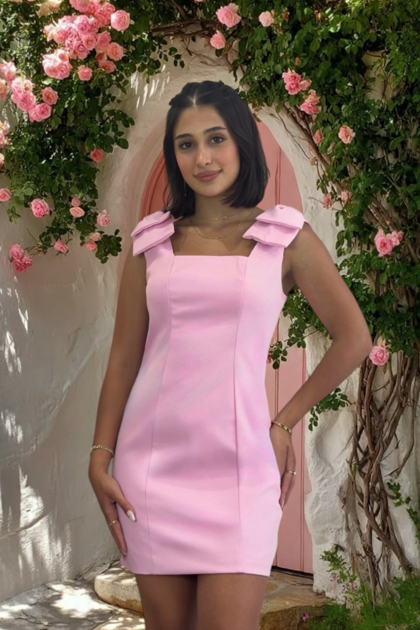 Woman in a pink dress standing in front of floral decorations